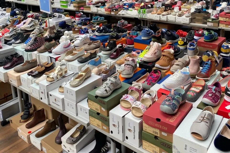 Rayons d'un magasin de chaussures, des dizaines de paires neuves posées sur leurs boîtes
