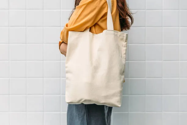Personne portant un tote bag en coton écru à l'épaule