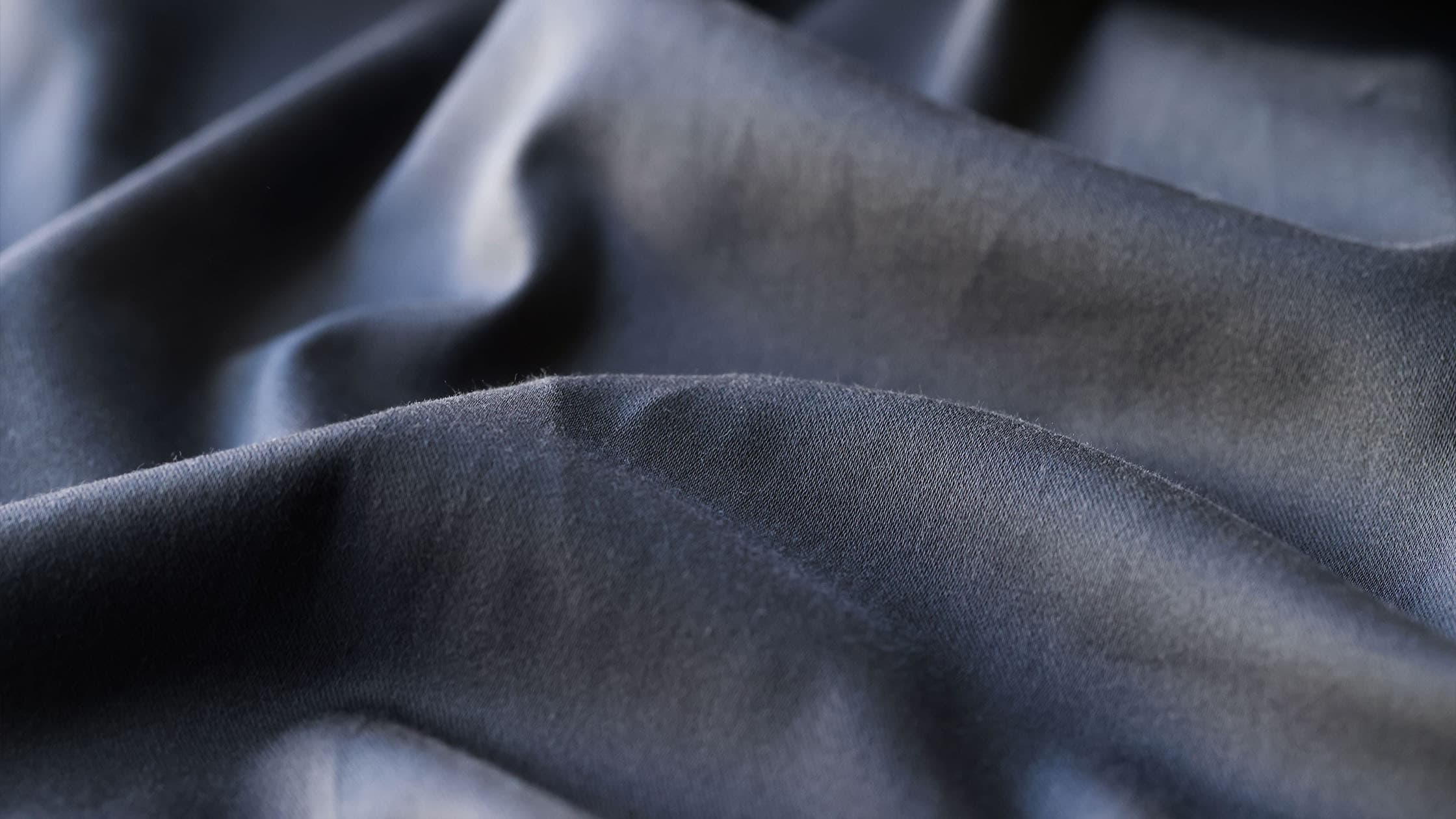 Gros plan sur un tissu en polyester, montrant le tissage régulier de fibres synthétiques brillantes.